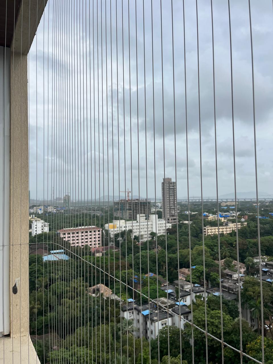 Invisible grill steel cables across a high-rise balcony with city view